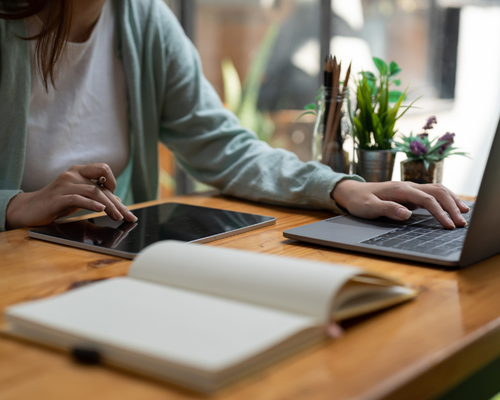 Photo of a woman working on a laptop and tablet